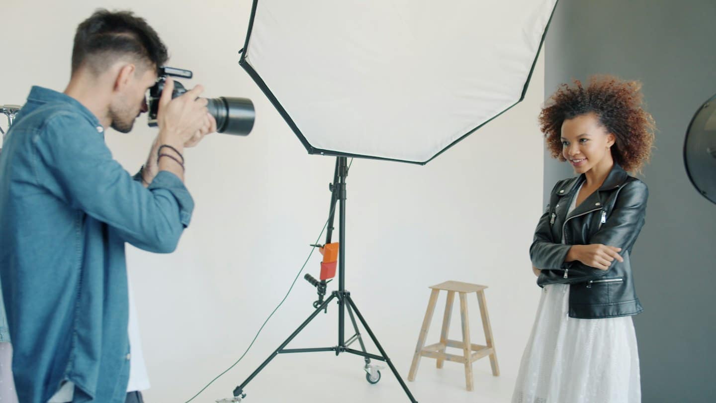 Fotografo che scatta una foto a una modella sorridente in studio.